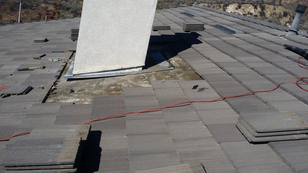 Worn flashing and water staining at the base of a chimney showing an active leak point