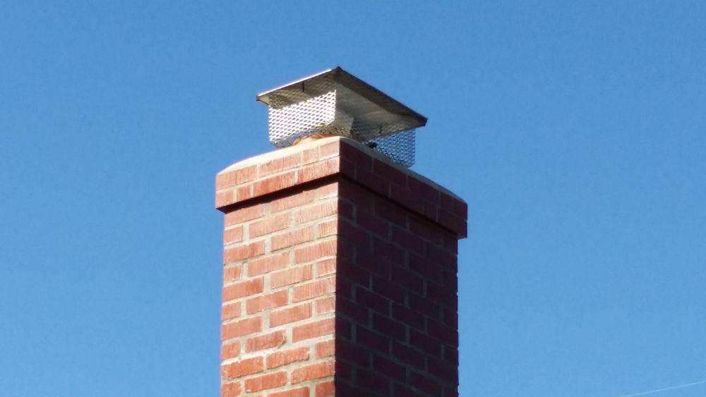 New stainless steel mesh chimney cap installed on a red brick chimney