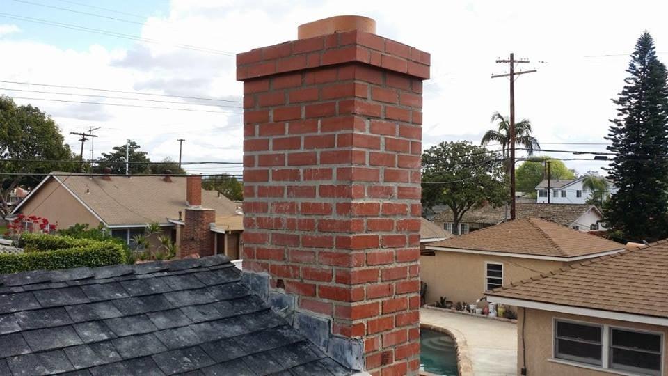 Rebuilt red brick chimney exterior overlooking a backyard pool