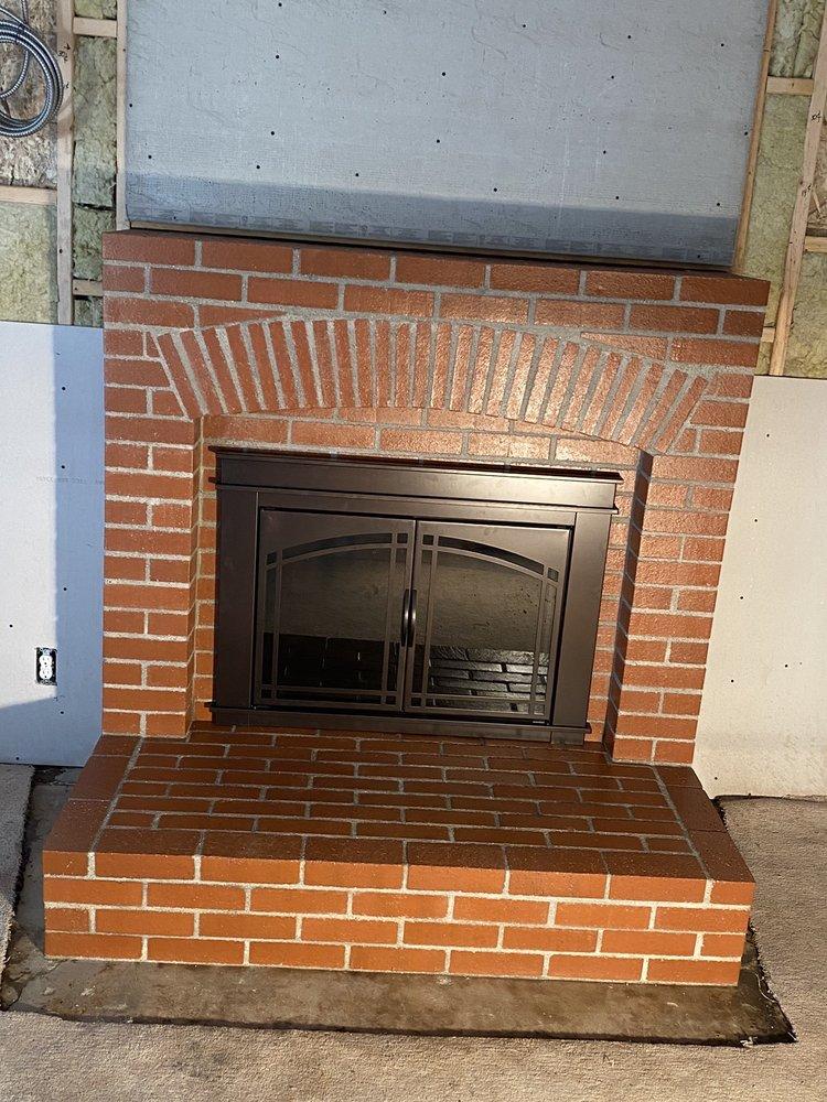 Finished fireplace with a new brick arch and glass insert doors
